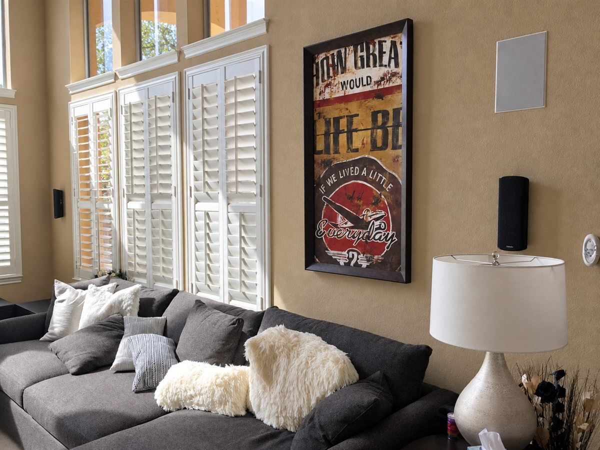 Living room with architectural shutters, a wall-mounted speaker and media furnishings